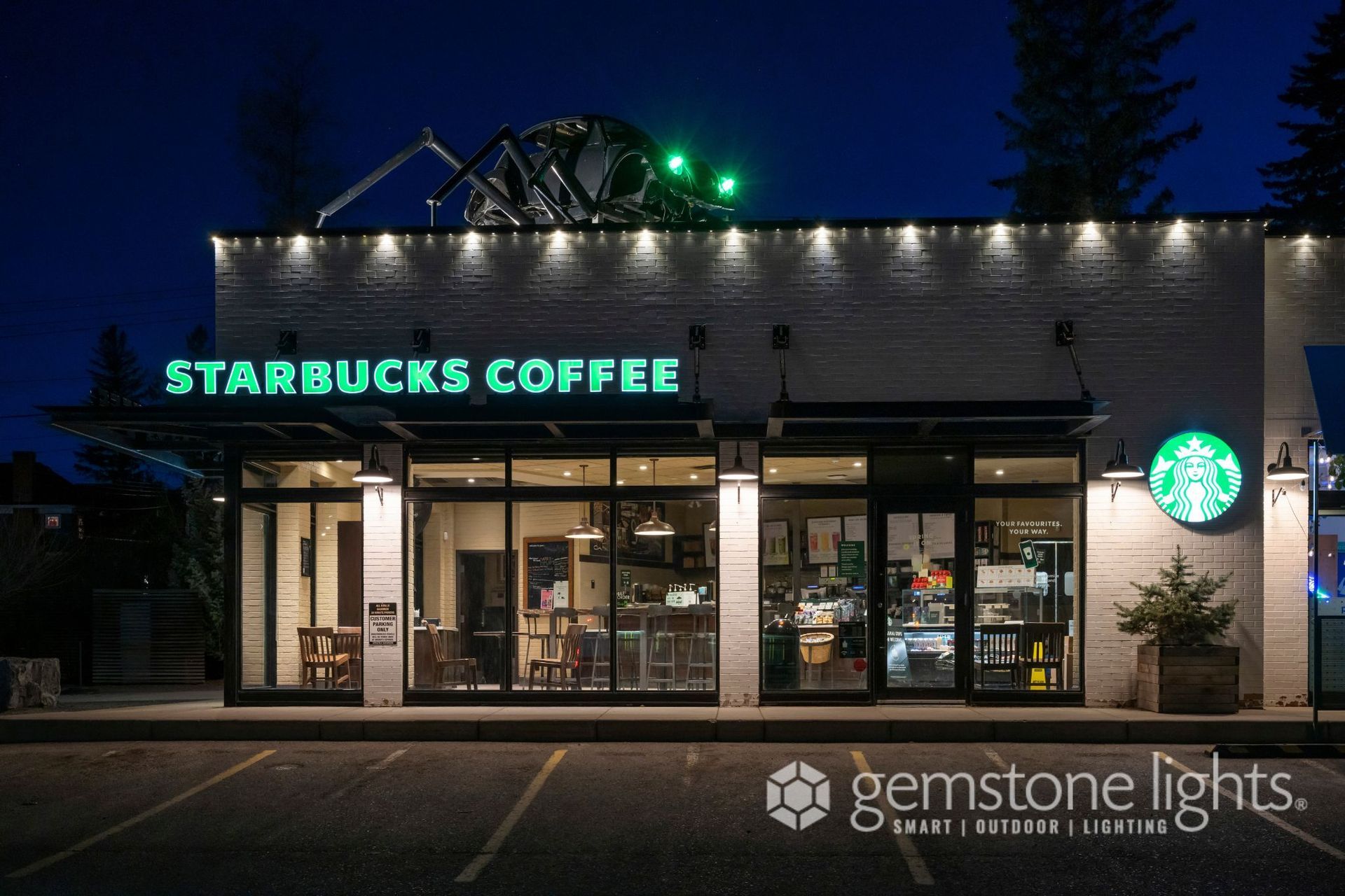 A starbucks coffee shop is lit up at night.