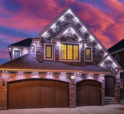 A large house with two garage doors is lit up at night.