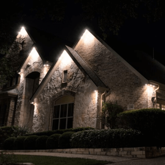 A large brick house is lit up at night