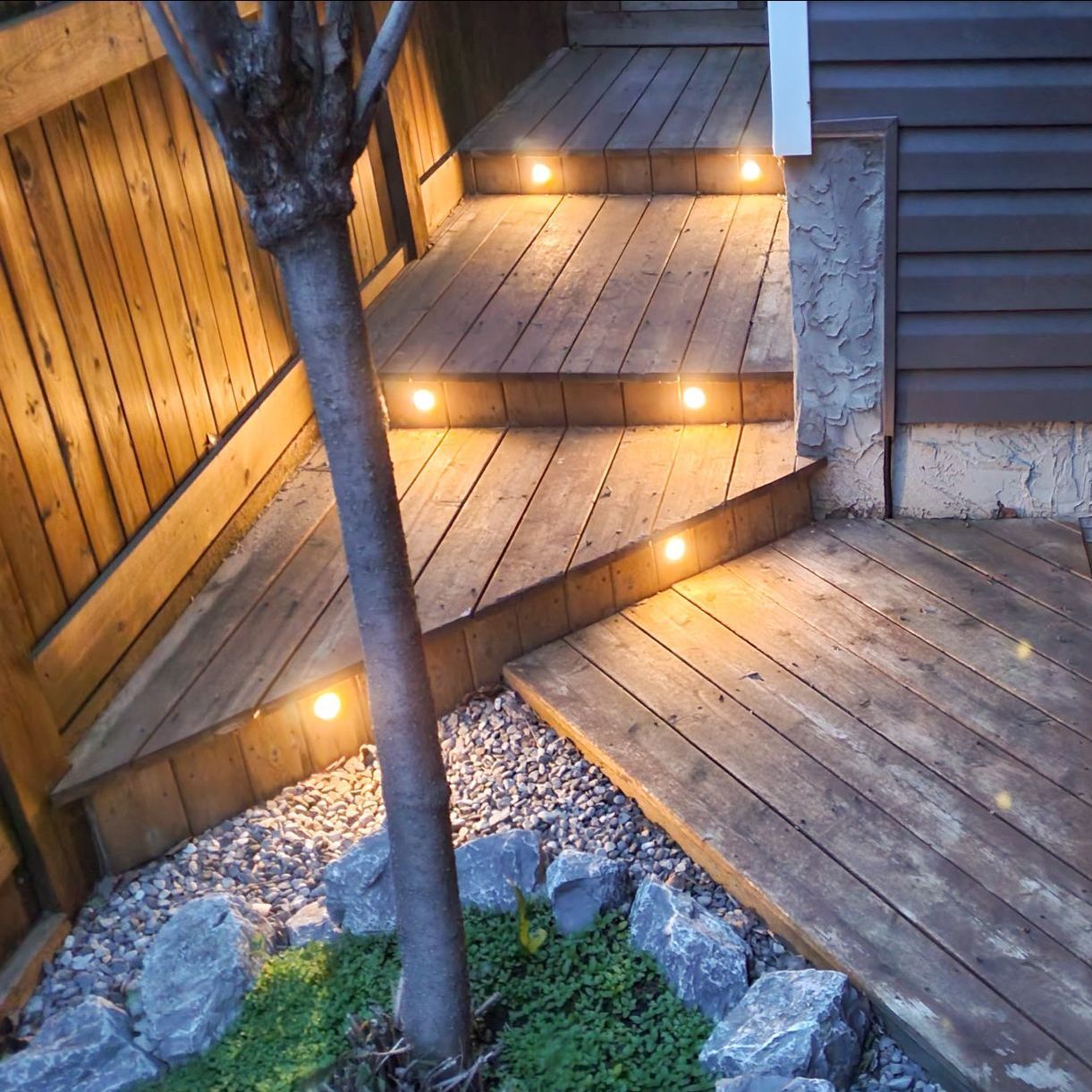 A wooden deck with stairs that are lit up at night