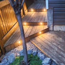 A wooden deck with stairs that are lit up at night