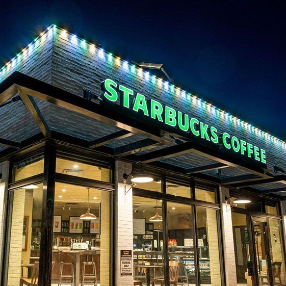 A starbucks coffee shop is lit up at night.