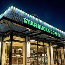 A starbucks coffee shop is lit up at night.