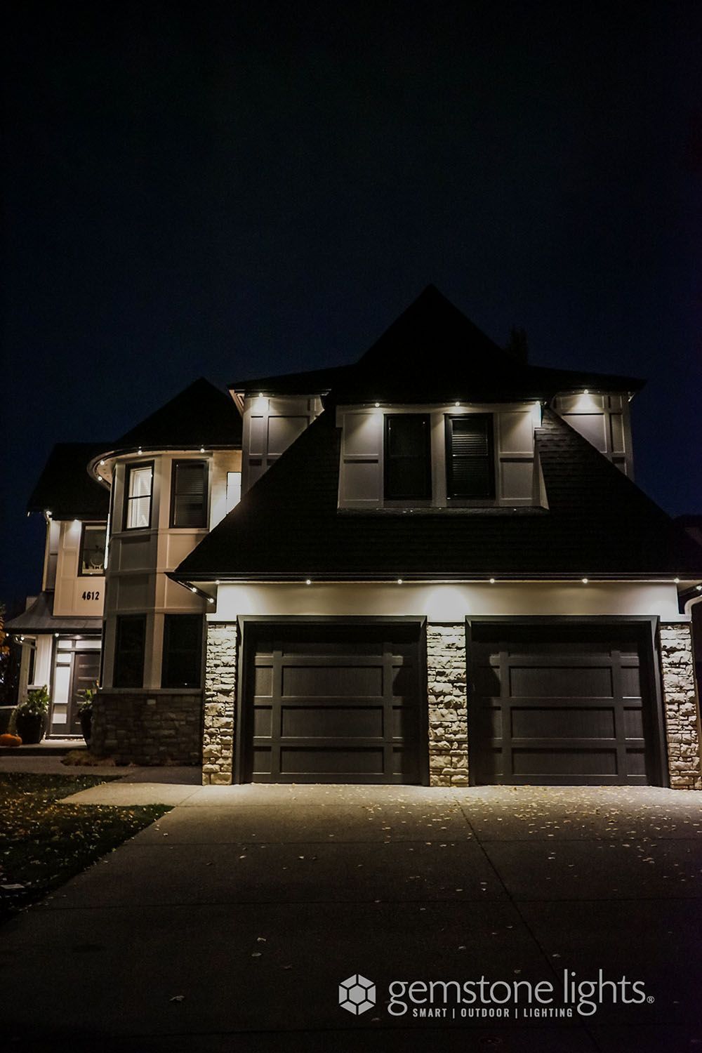 A large house with two garage doors is lit up at night.