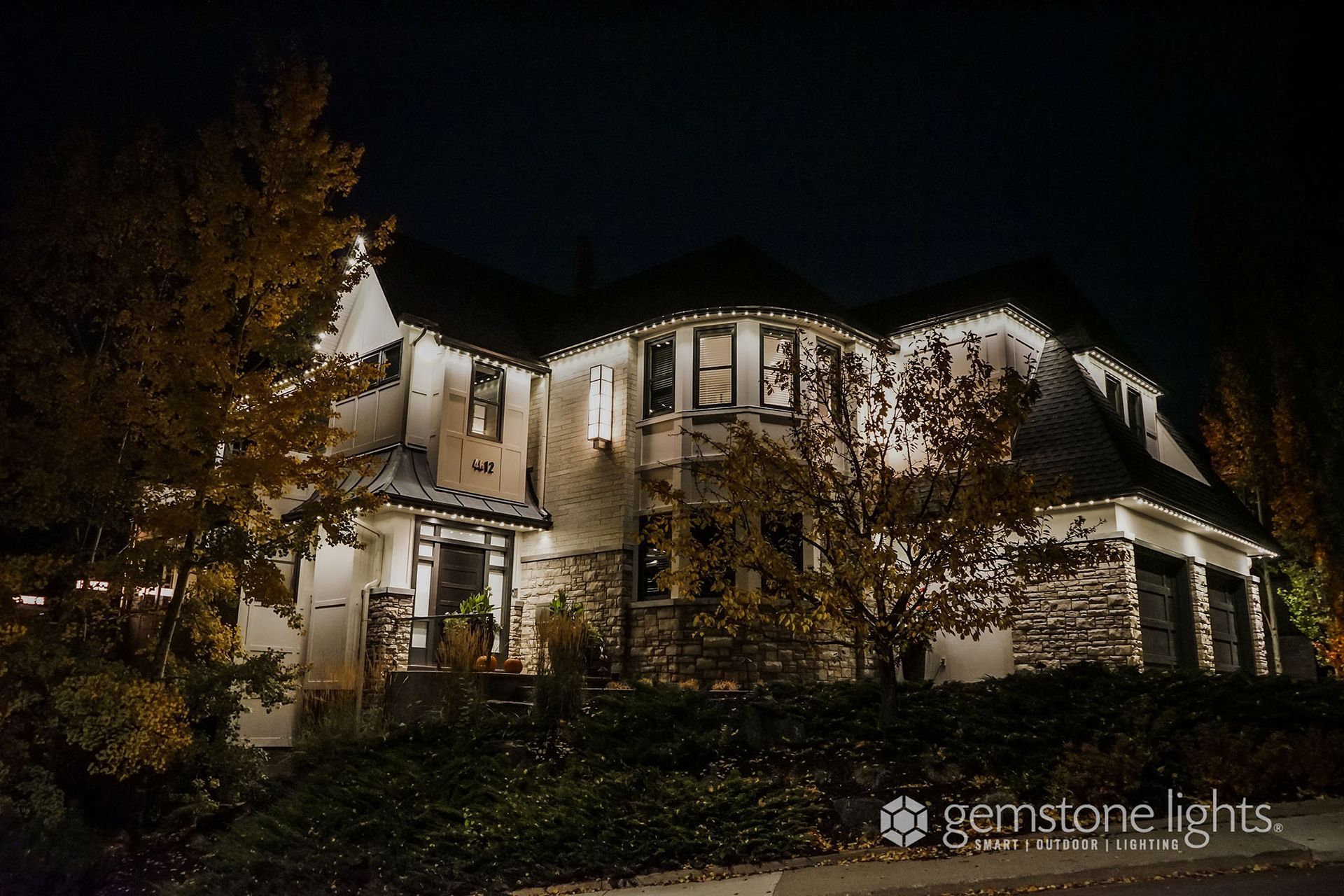 A large house is lit up at night with christmas lights.