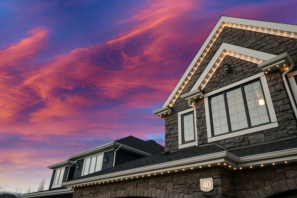 A large house with lights on the roof and a sunset in the background.