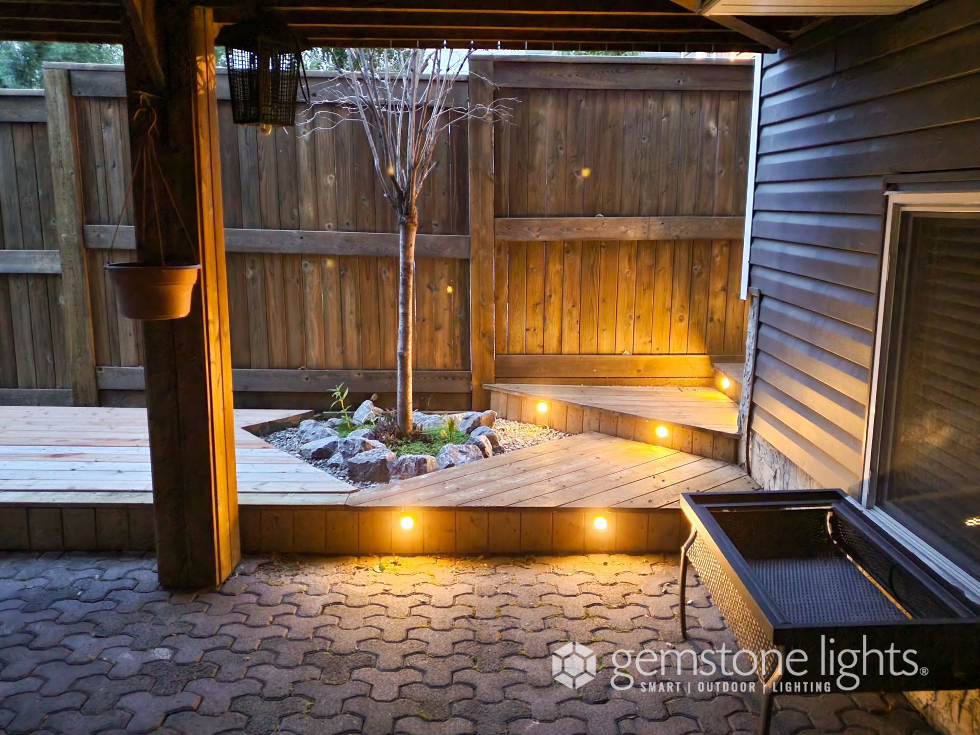 A backyard with a wooden fence and lights on the ground