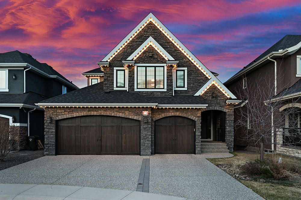A large house with two garage doors and a sunset in the background.