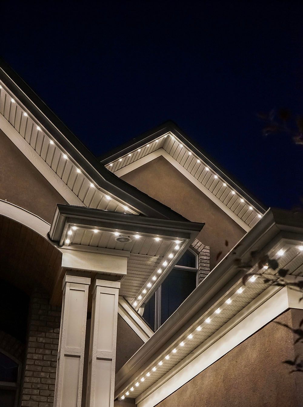 The roof of a house is lit up at night with christmas lights.