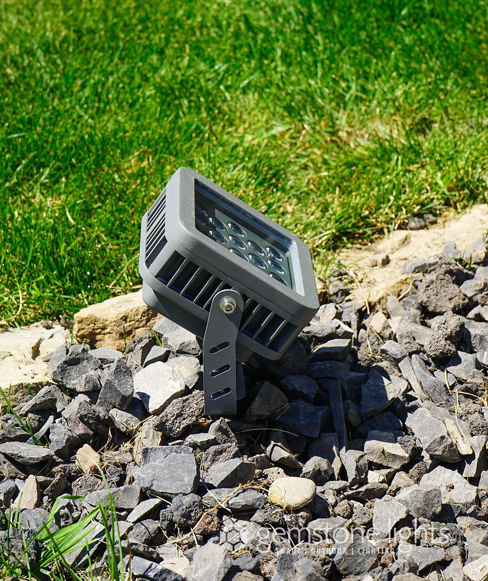 A light is sitting on top of a pile of rocks next to a lawn.