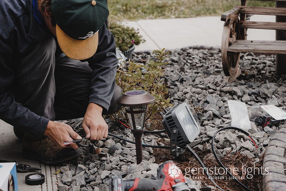 A man is working on a garden light with a drill.