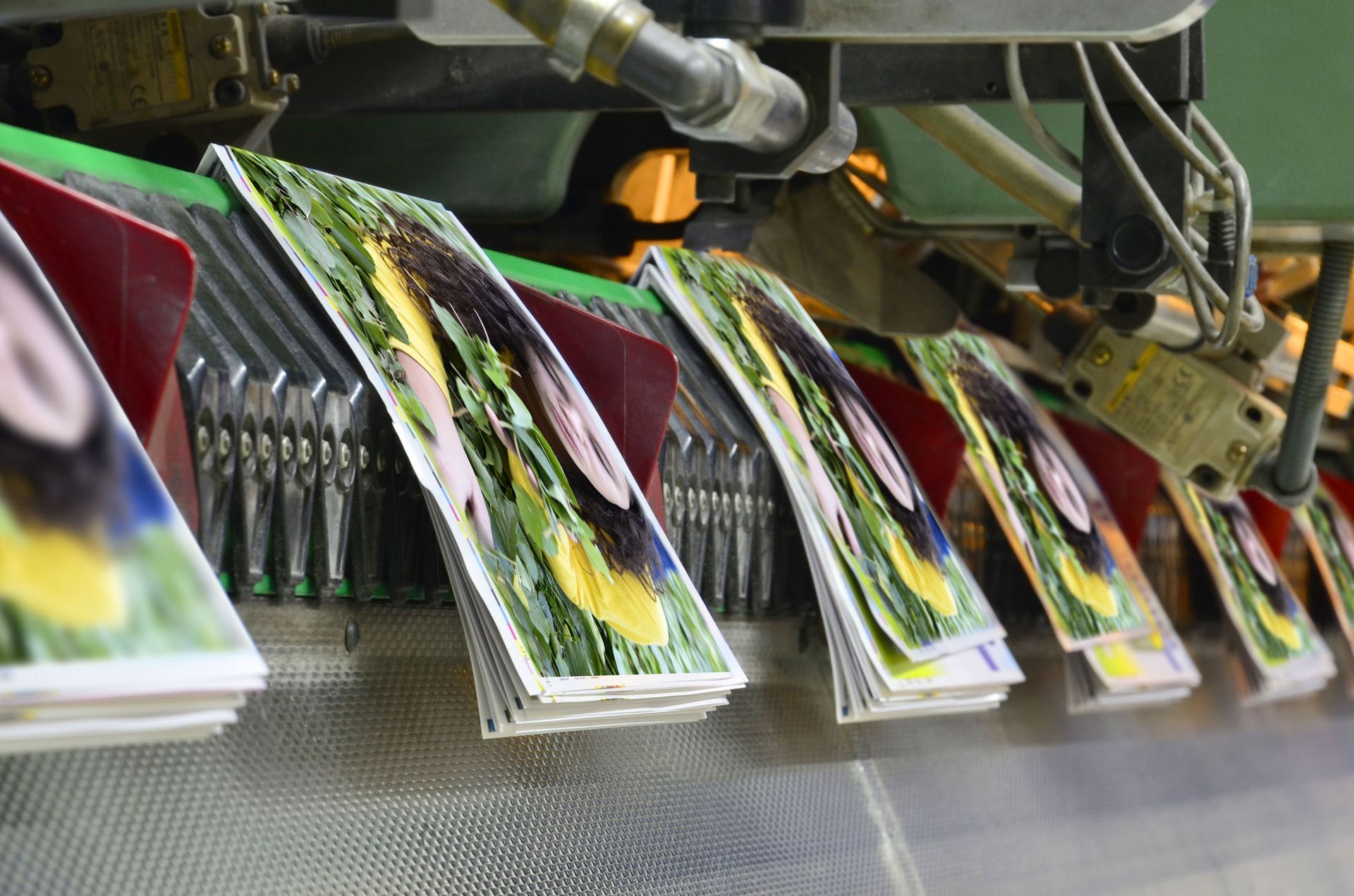 Printed magazines being stacked on a conveyor belt, showing colorful covers.