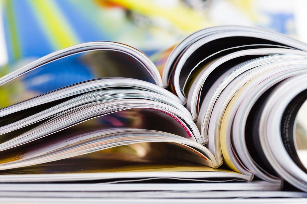 Pile of open magazines, colorful pages visible, close-up view.