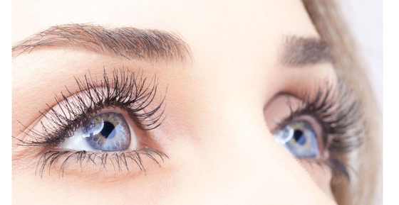 A close up of a woman 's blue eye with long eyelashes.