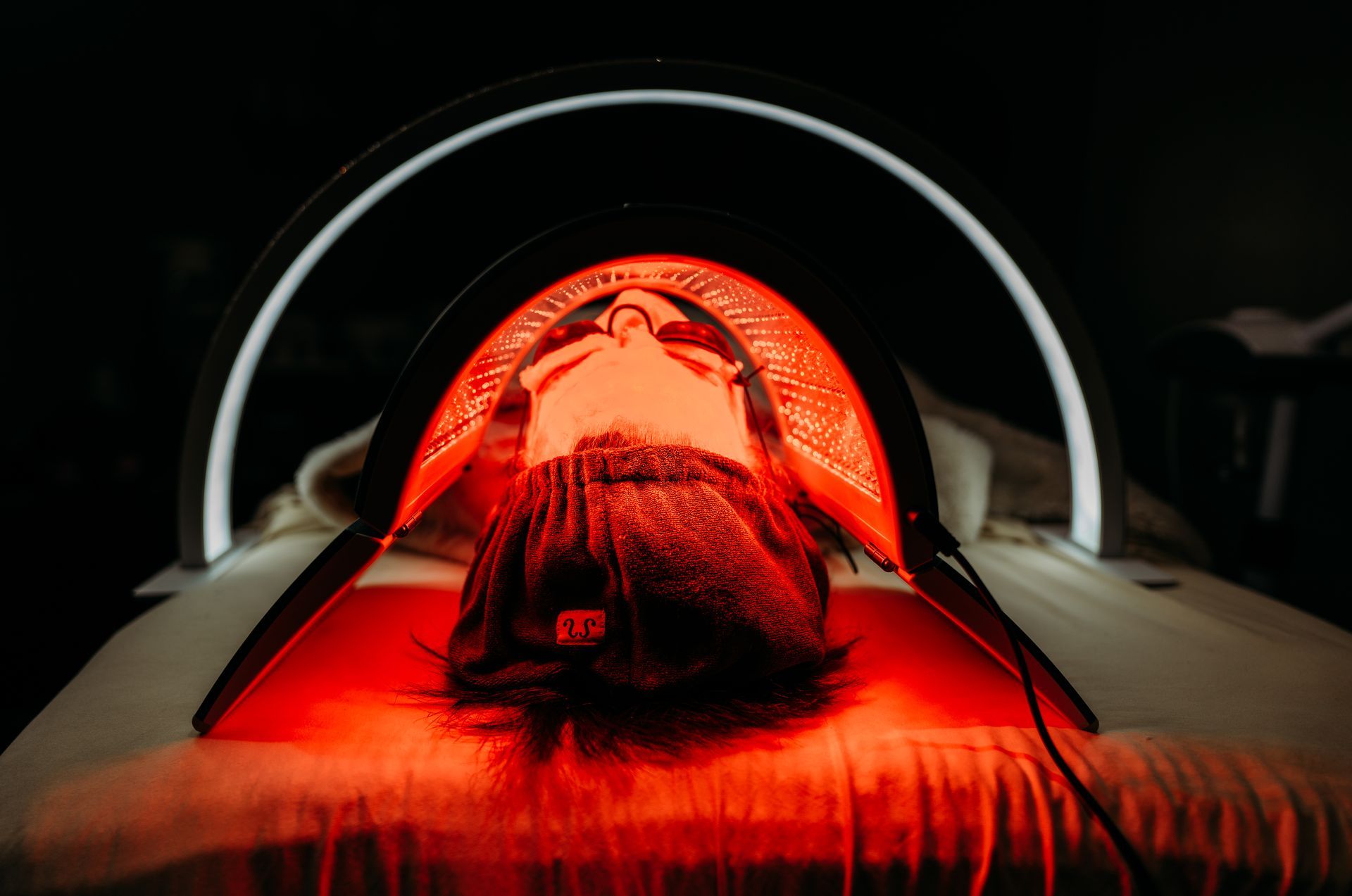 A woman is laying in a bed under a red light.