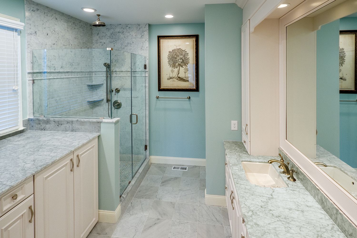 Modern bathroom with glass shower, double vanity, large mirror, and light blue walls