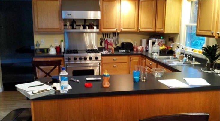 Modern kitchen with wooden cabinets, black island countertop, stainless stove, and sink by a window