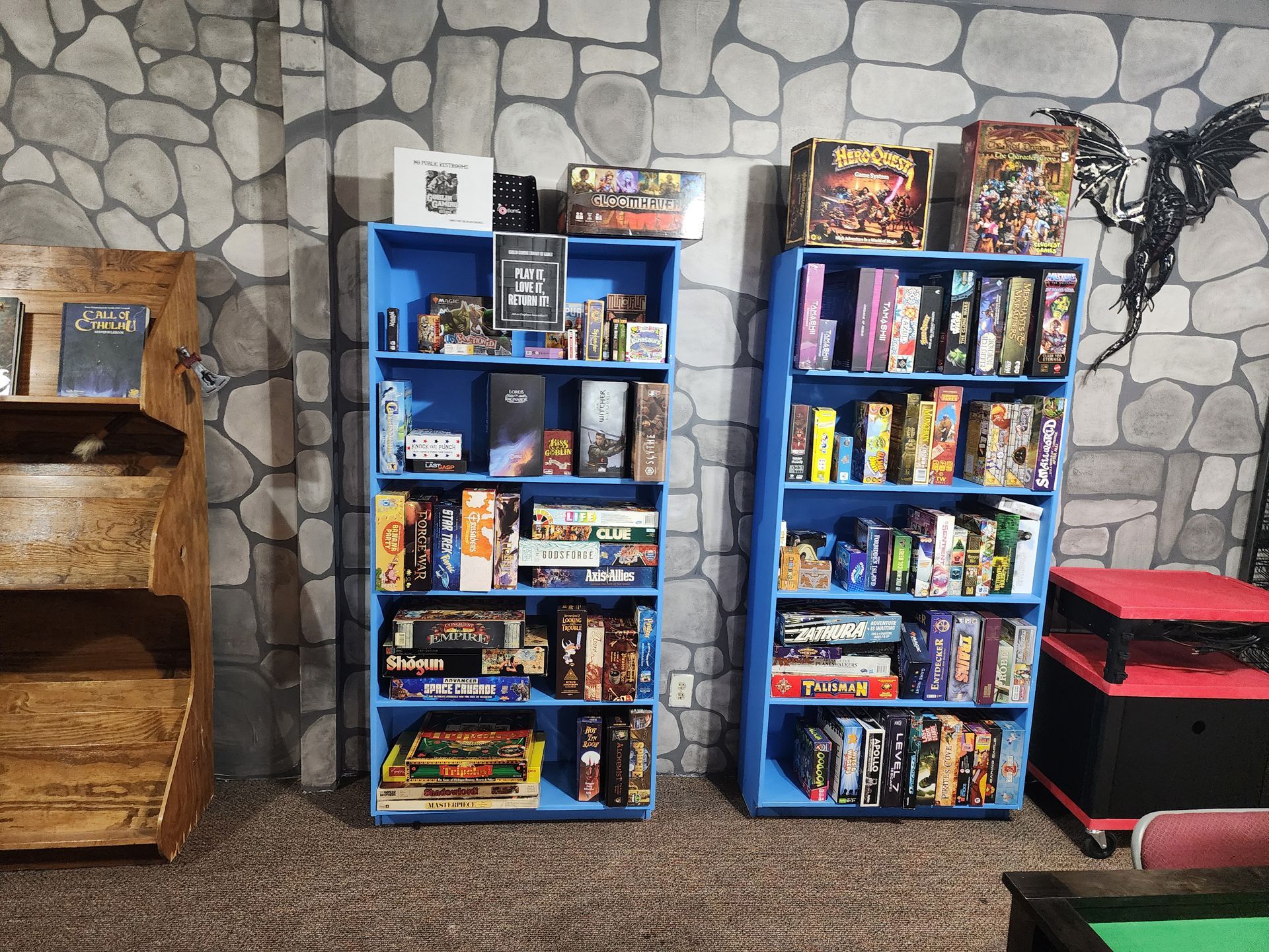 Two blue shelves filled with lots of board games in a room