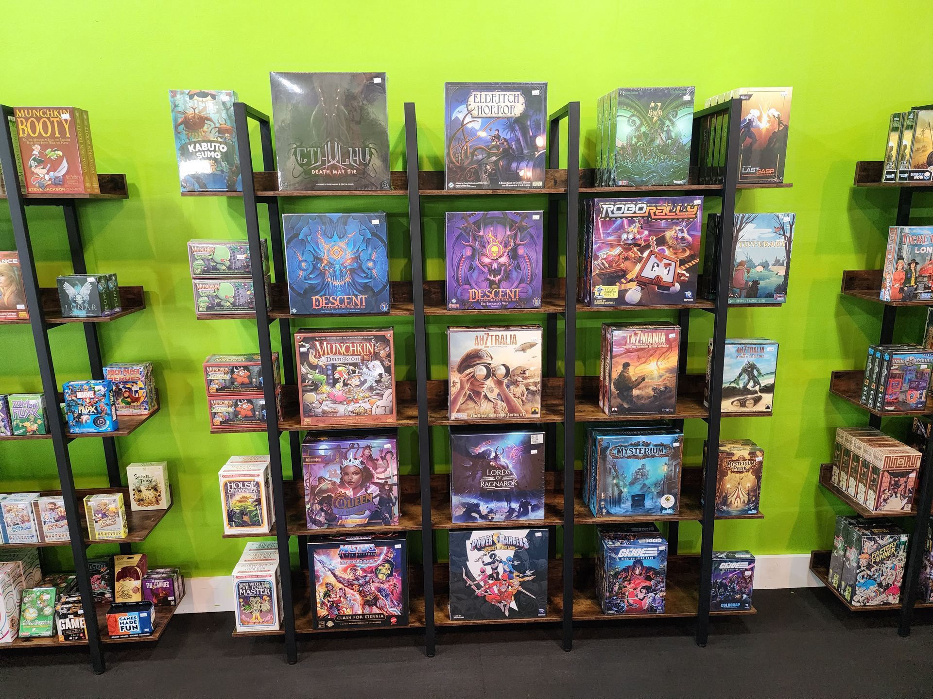 A shelf filled with lots of board games against a green wall