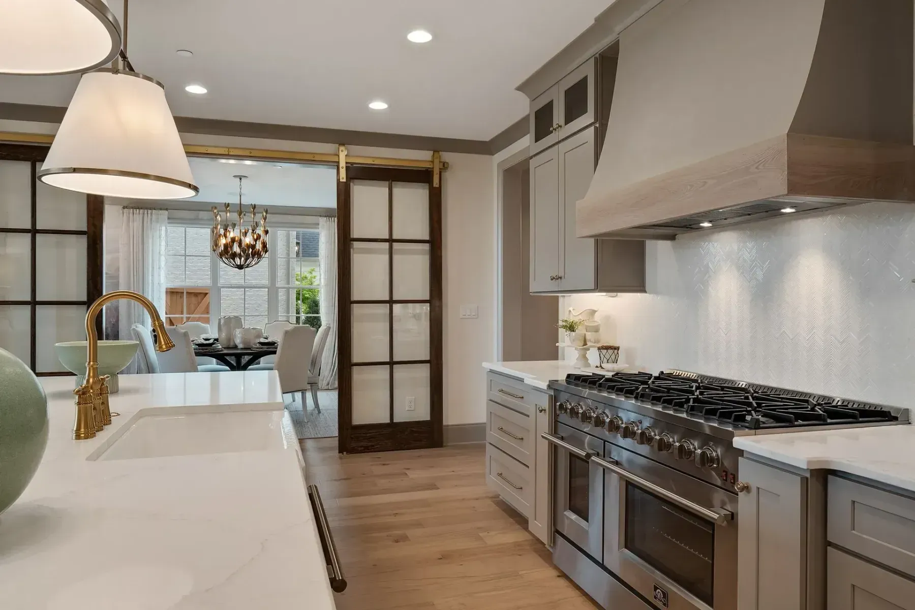 Kitchen with a stainless steel range, white countertops, light wood floors, and a view of the dining room.