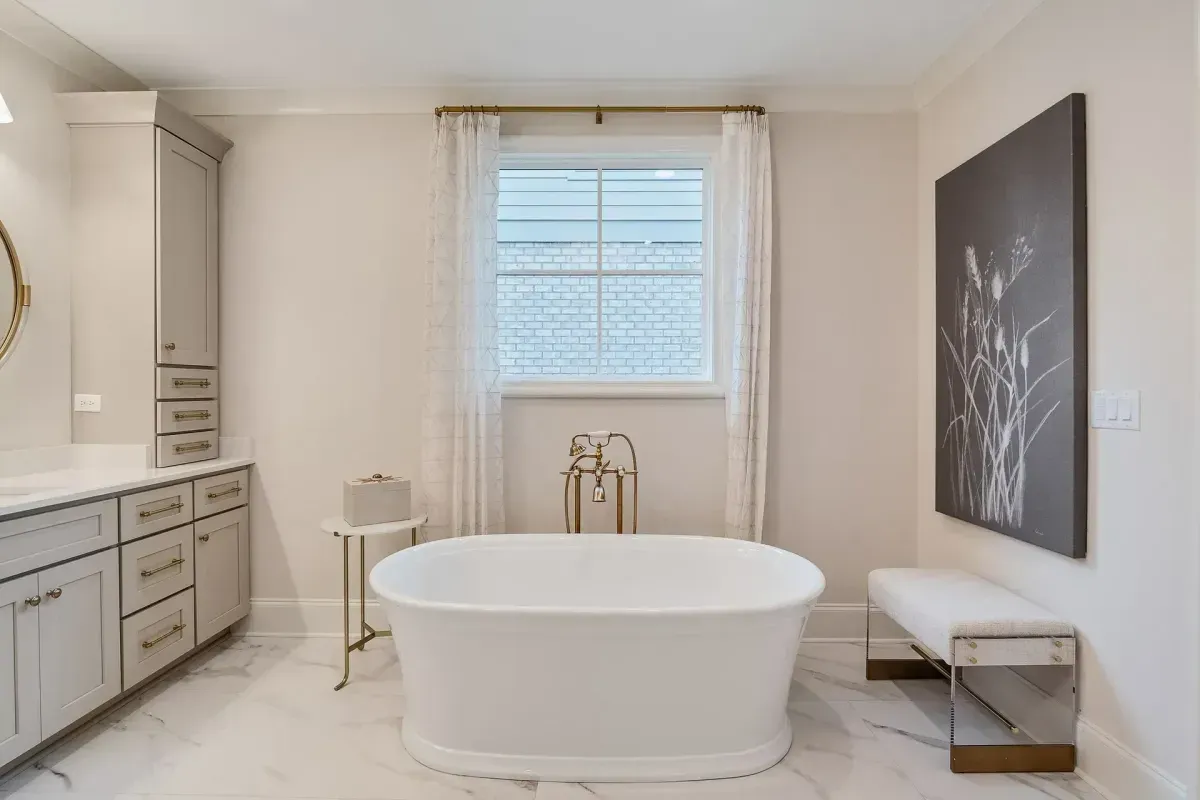 Spacious, bright bathroom with a white soaking tub, marble floor, and light-colored walls.