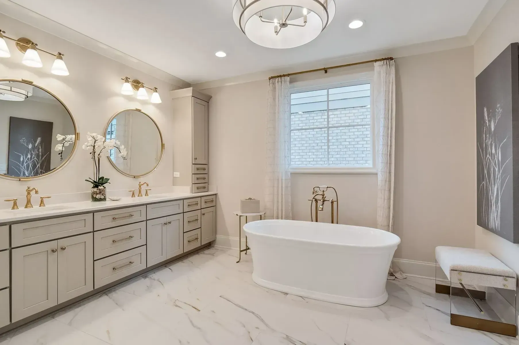 Elegant bathroom with a white soaking tub, double vanity, and gold fixtures.
