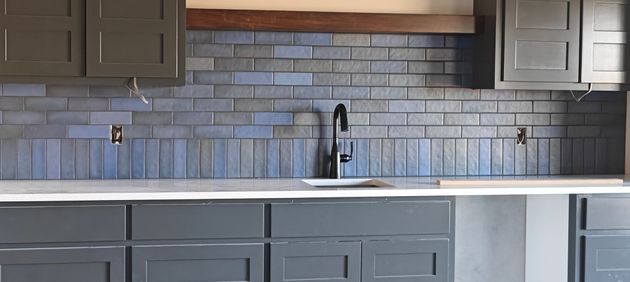 Modern kitchen with gray cabinets, white countertop, and blue-gray tile backsplash