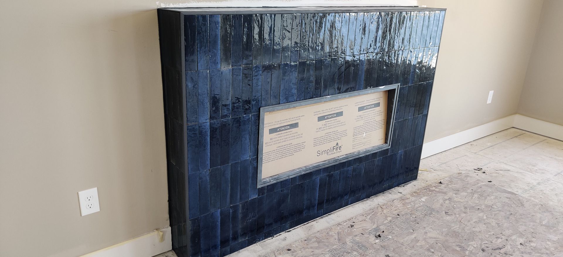 Dark blue built-in fireplace or cabinet with a beige inset panel in a sparsely furnished room.