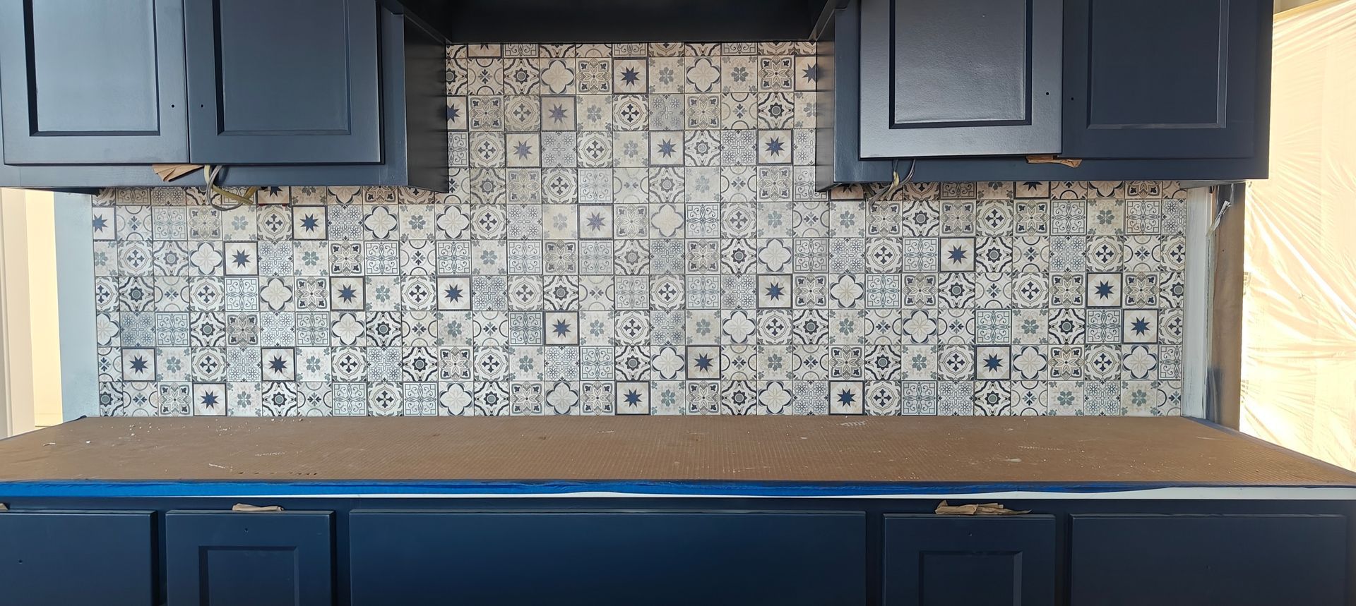 Kitchen with dark blue cabinets, light wood countertops, and patterned tile backsplash.