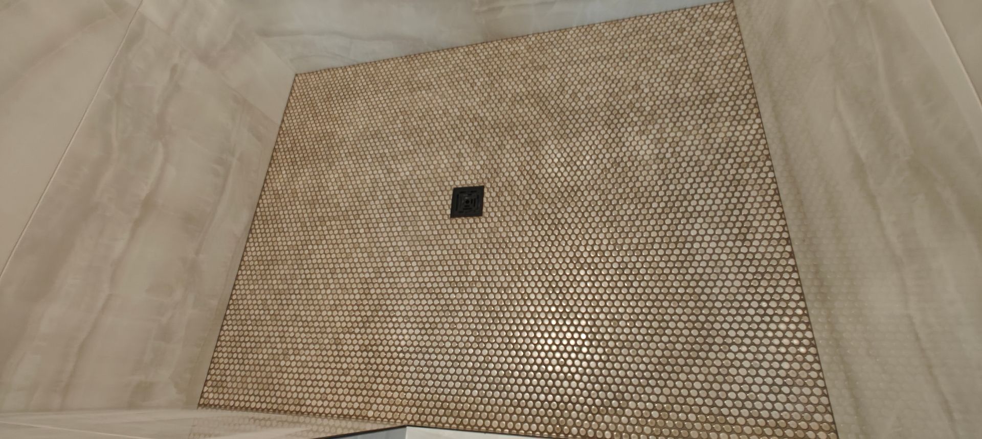 Brown woven mat with a small black square near the center on a beige floor.