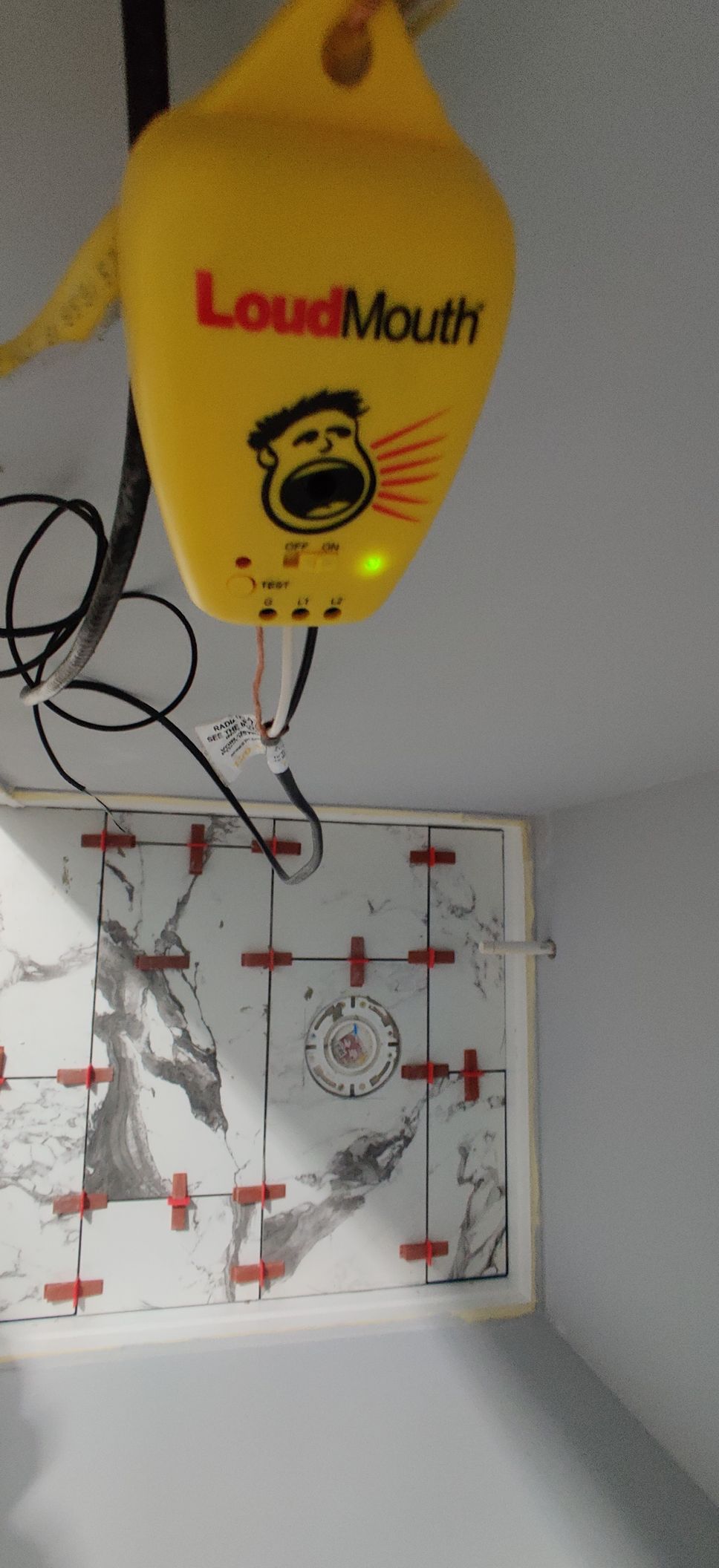 Yellow LoudMouth balloon above a wall-mounted target board with arrows and cords.