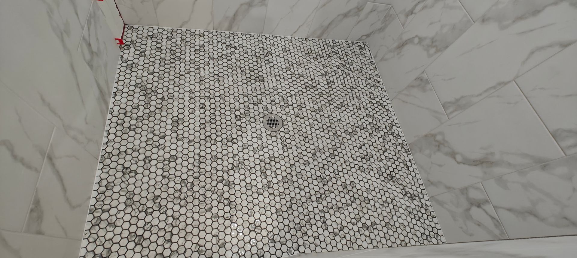 Marble-tiled corner with a black-and-white patterned strip on the floor or wall.