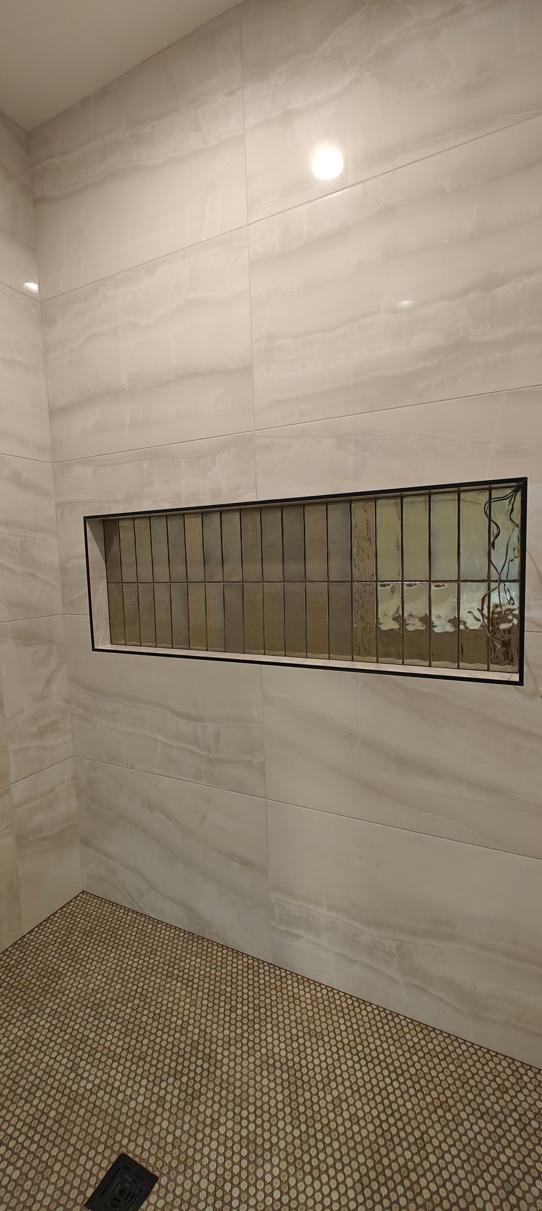 Modern tiled bathroom with a long rectangular mirror and patterned floor tiles.