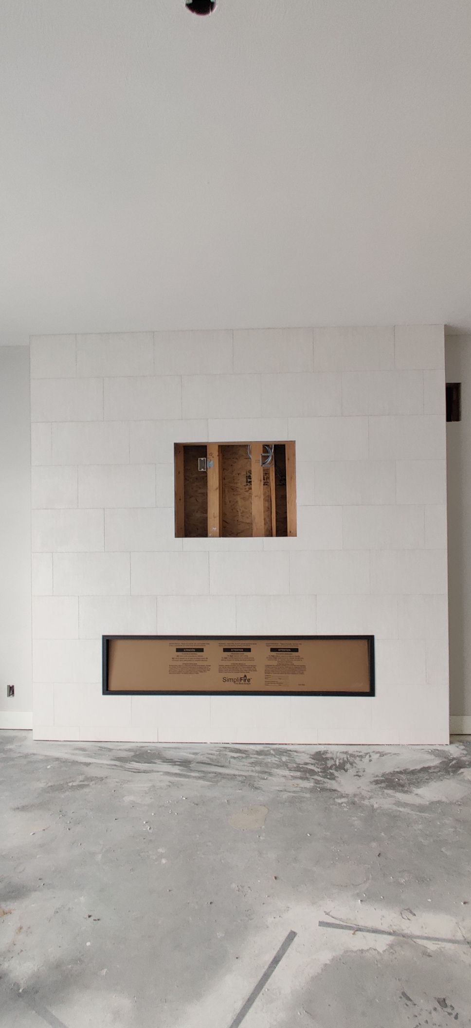 White interior wall with a small window opening above a built-in bench on a concrete floor.
