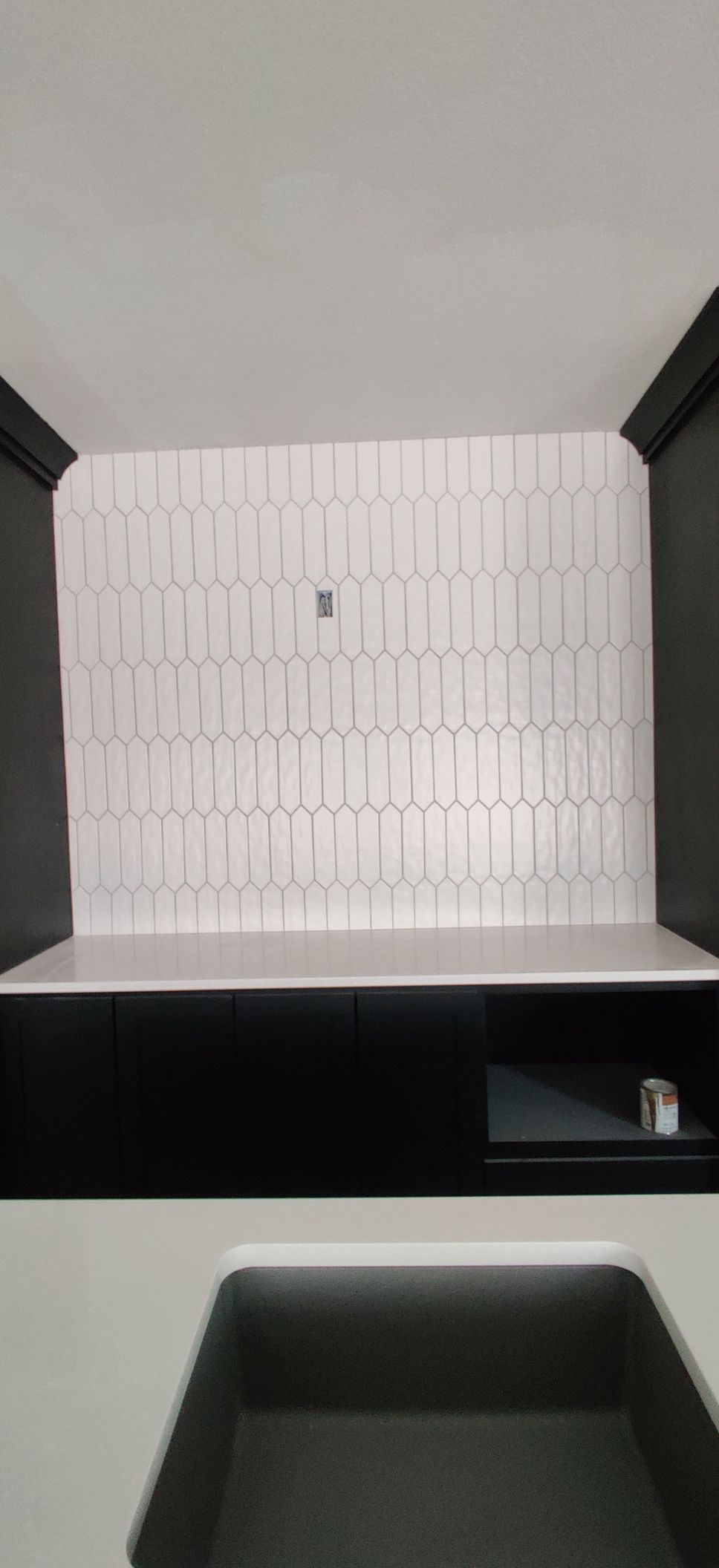 Empty black-and-white storage cubby with patterned white back panel and dark shelves.
