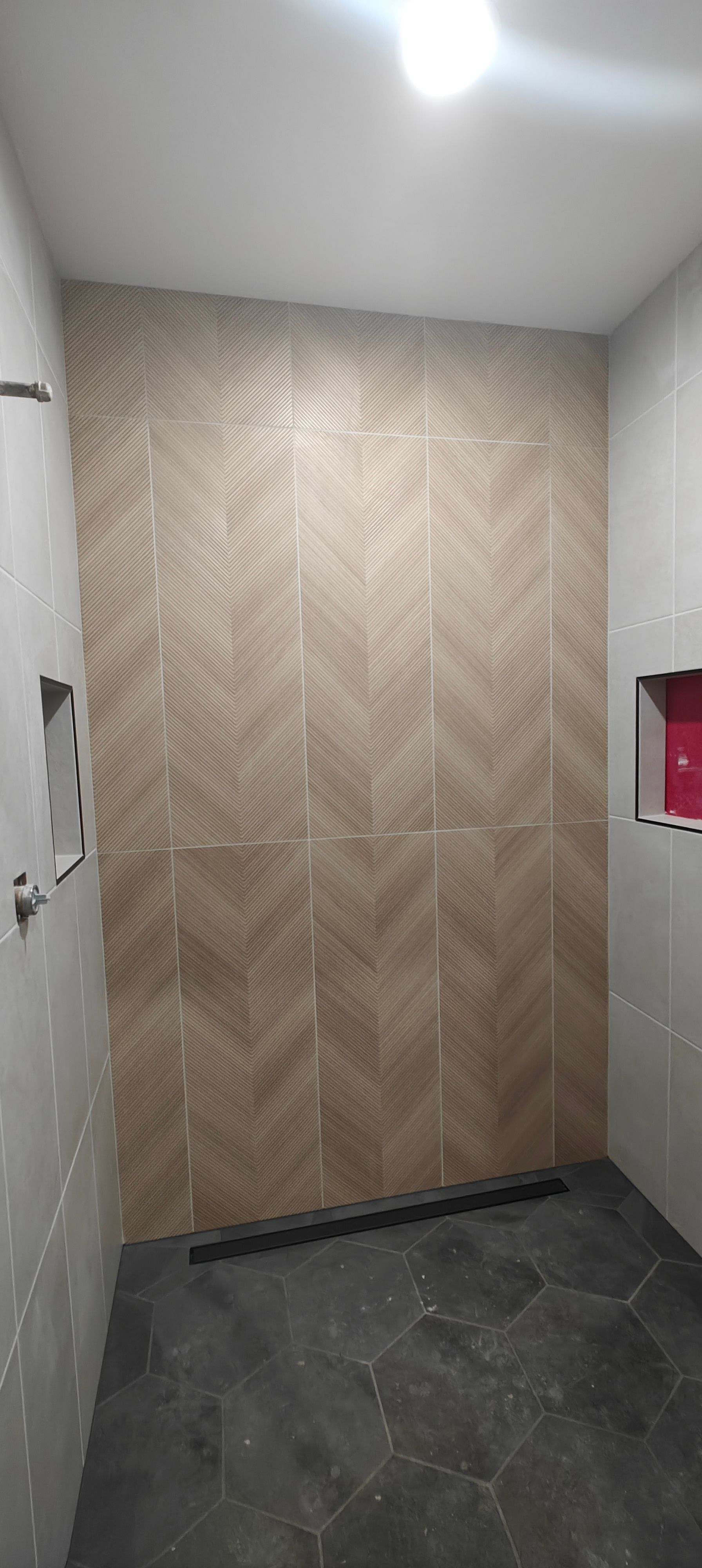 Small hallway with chevron wood wall paneling, dark tile floor, and white ceiling lights.