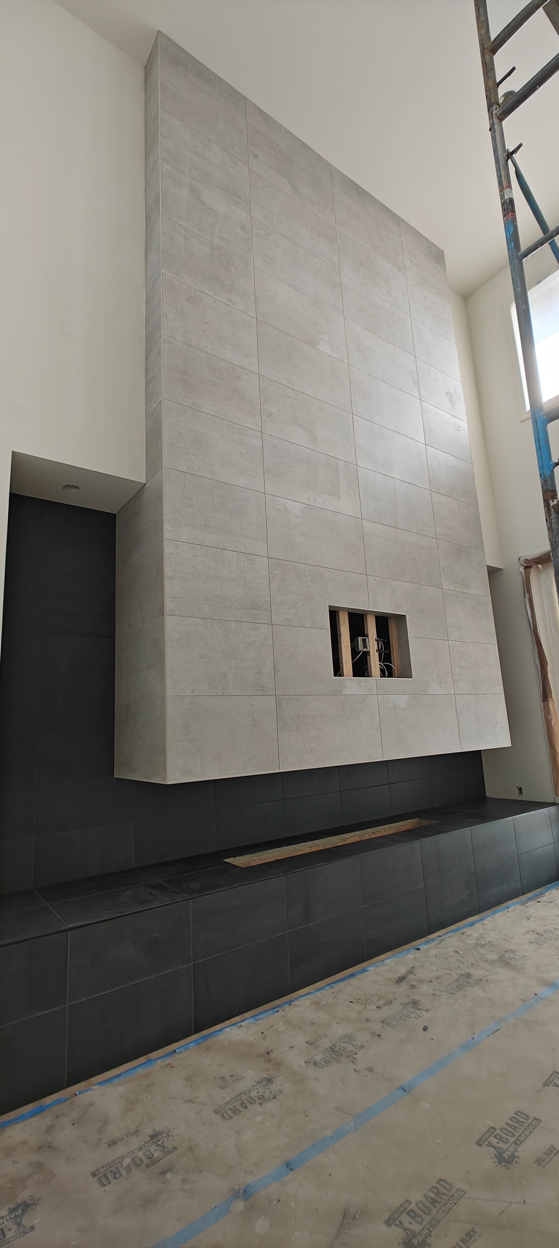 Large unfinished concrete wall inside a building, with a dark doorway and small utility openings near the bottom.