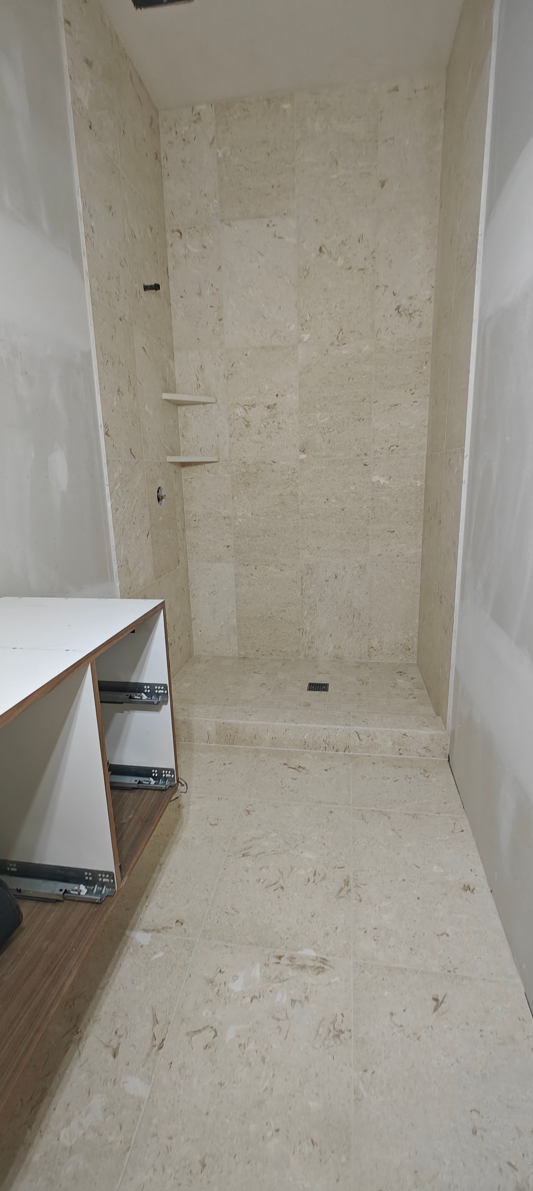 Narrow empty beige hallway or closet with white shelves and carpeted floor.