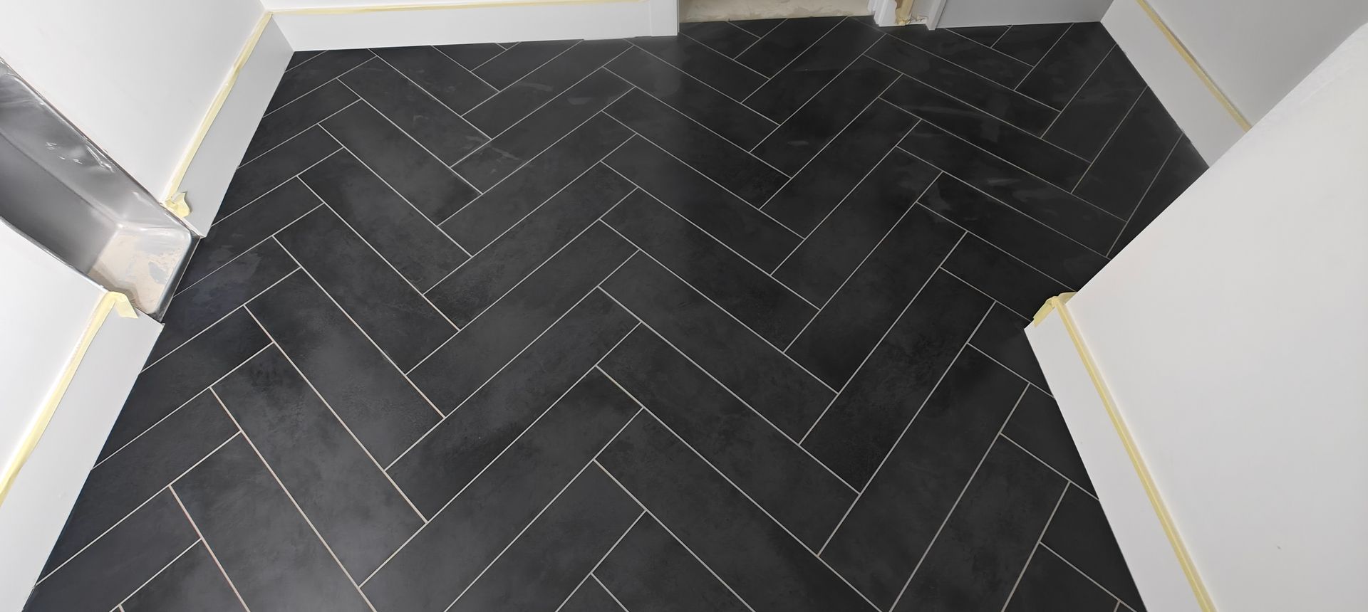 Black herringbone tile floor in a small white hallway or entryway.