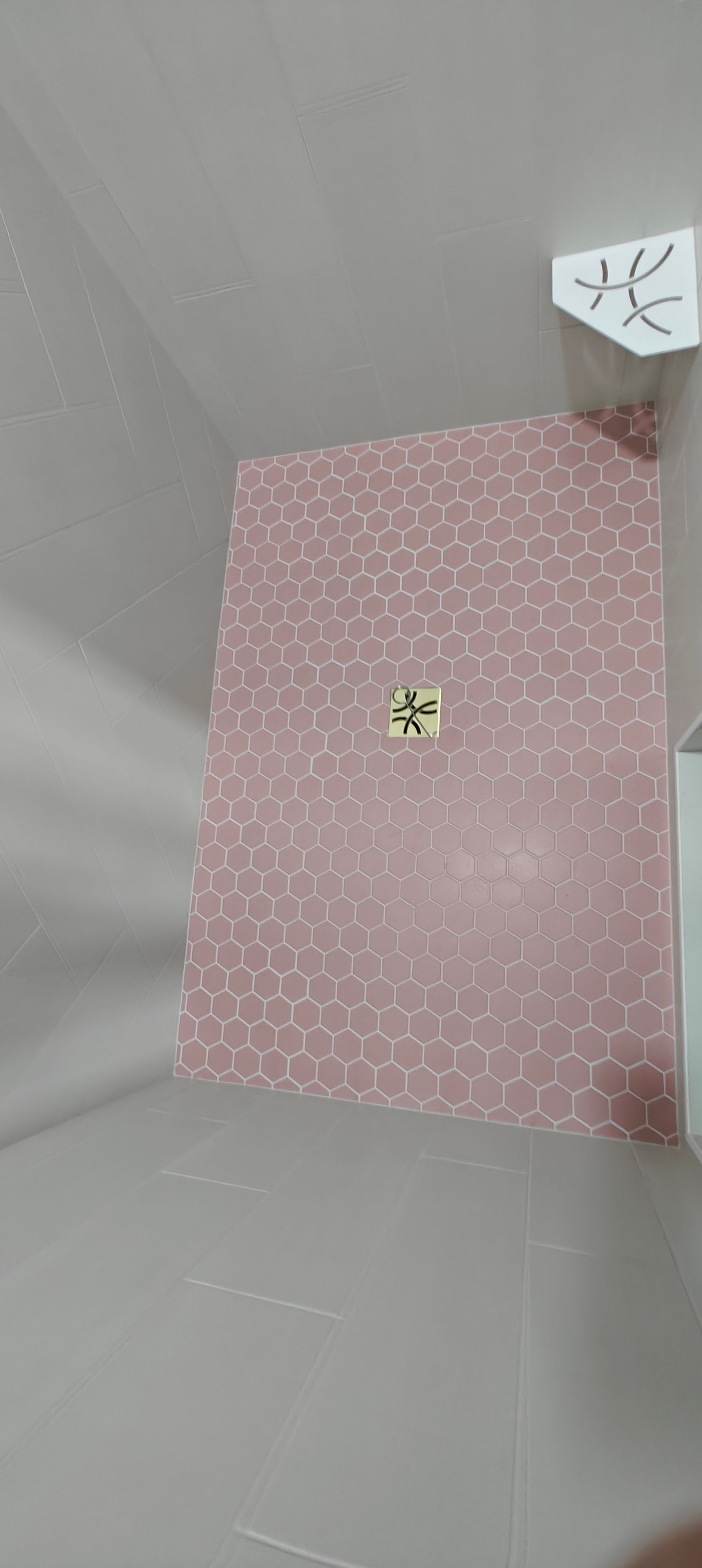Pink patterned mat on gray floor with a small object at the center and a white cube in the corner.