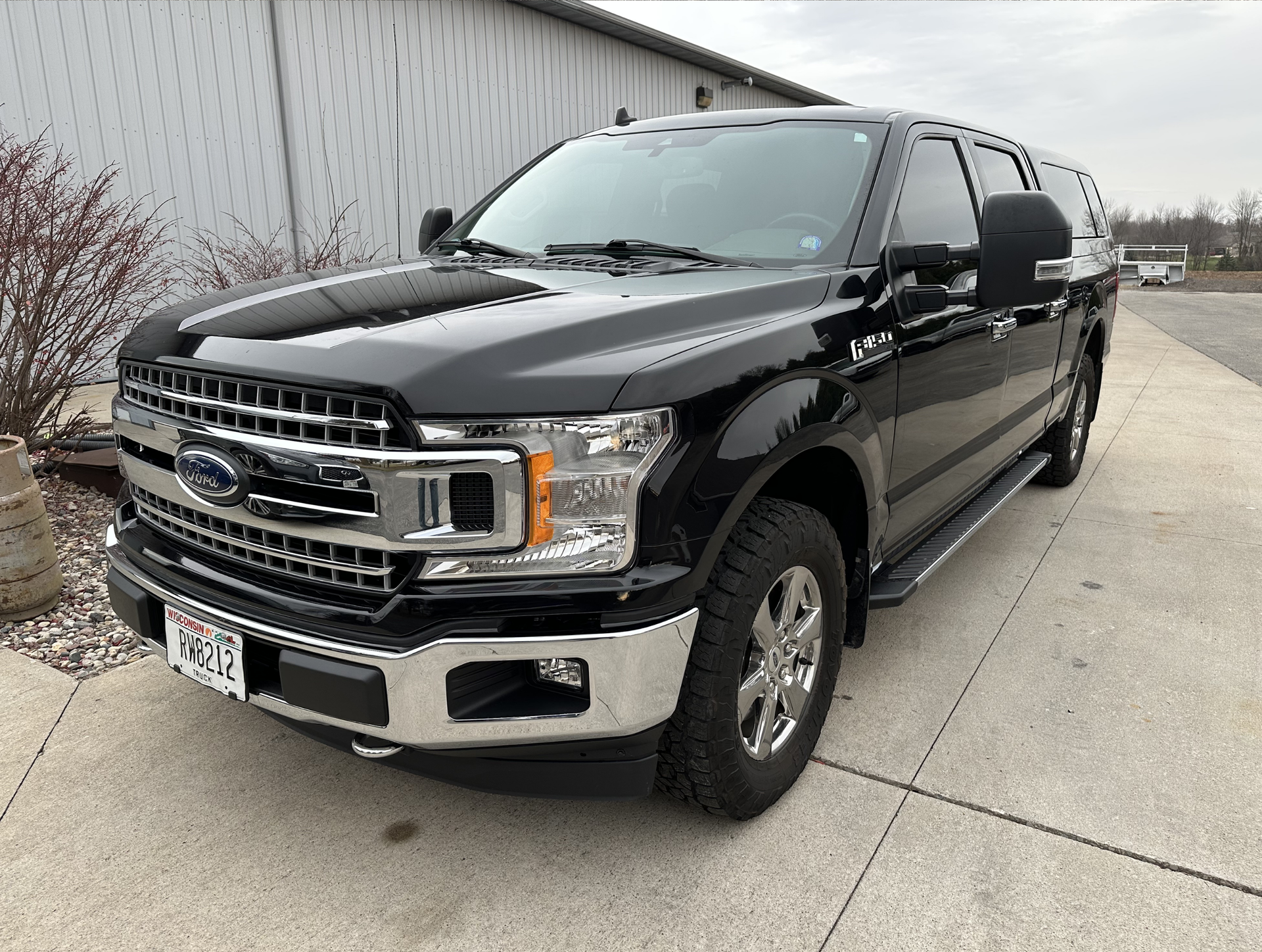 Black Ford F-150 truck parked in front of a building. Chrome grill, running boards, and wheels.