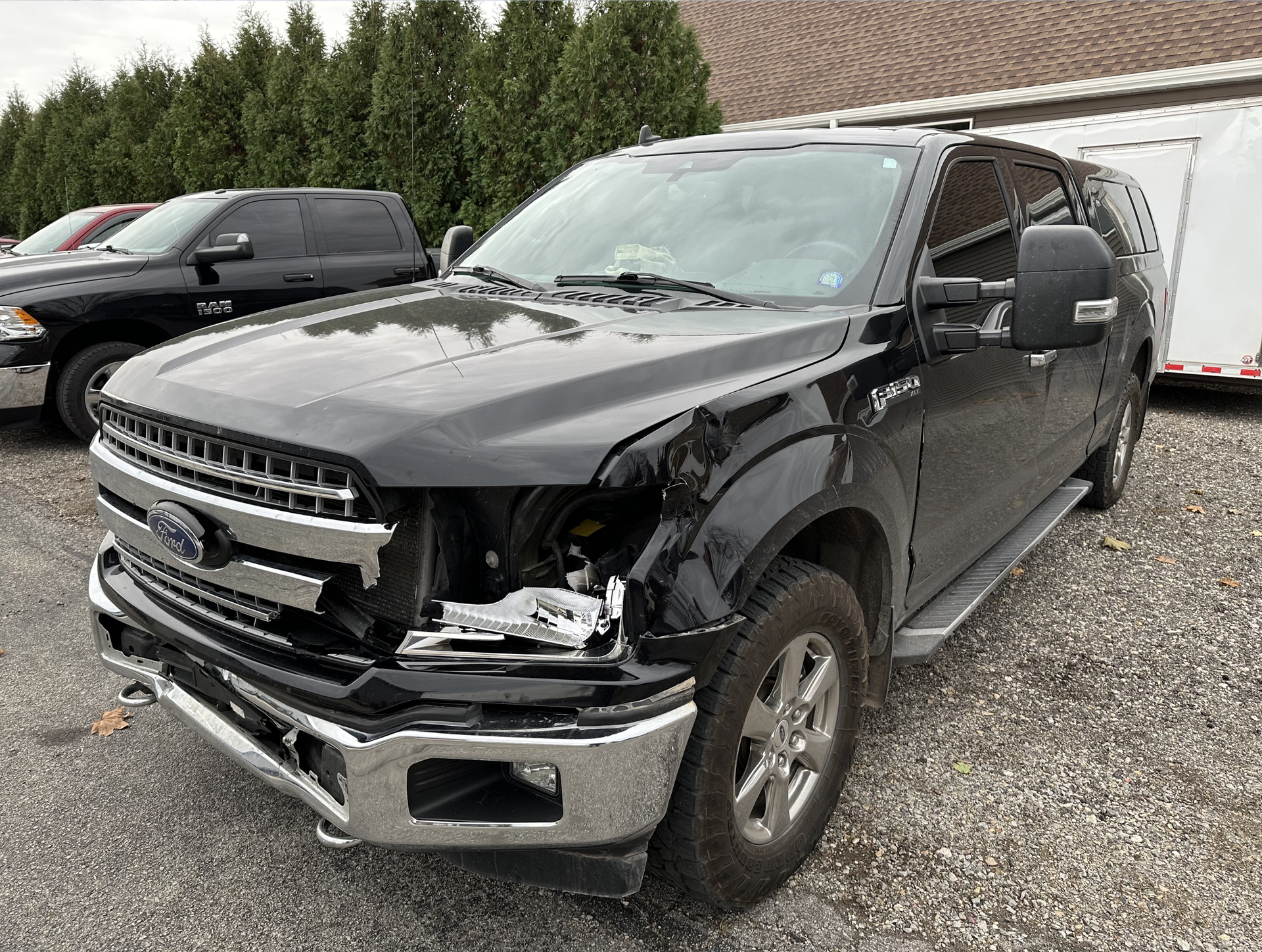 Black Ford pickup truck with front-end damage; parked outside a building.