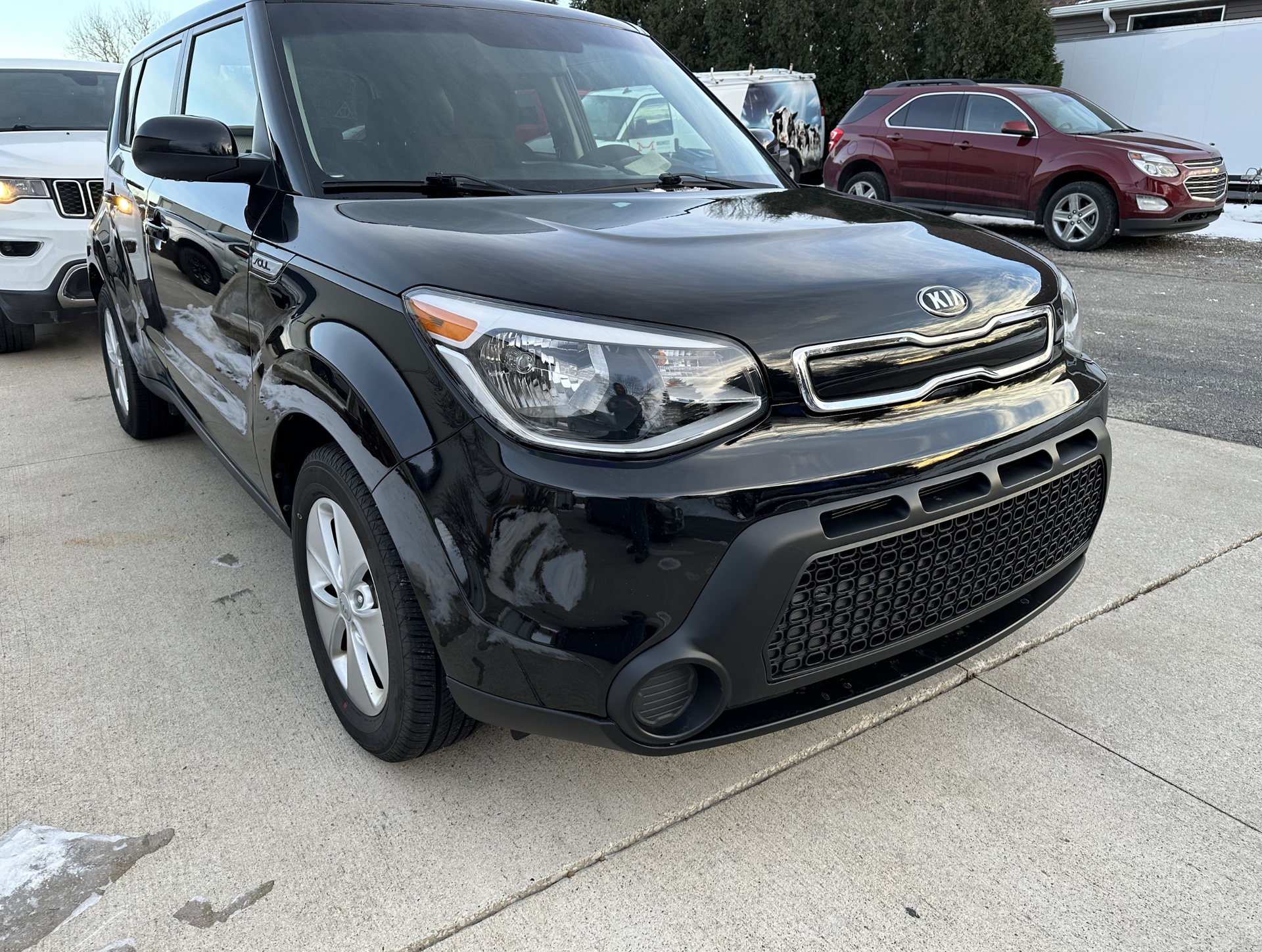 Black Kia Soul parked on pavement.