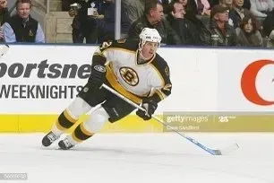 Hockey player in black, gold, and white Bruins uniform skates on ice.