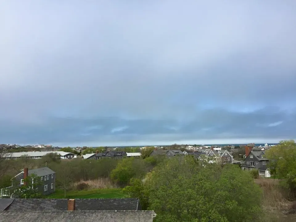Overcast view of a town with houses and trees under a cloudy sky.