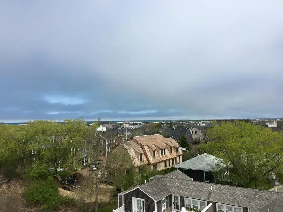 Overhead view of homes beneath a cloudy sky, with green trees.