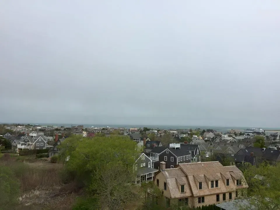 Overcast sky over a coastal town, seen from a high angle. Buildings with various roof colors.