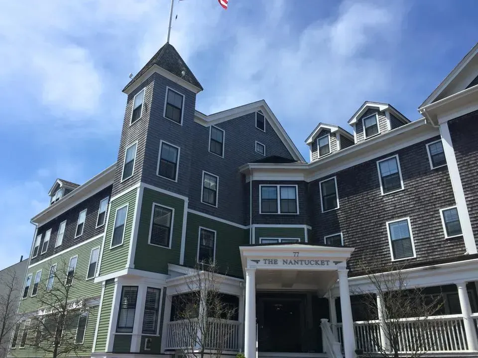 Hotel building with a multi-colored exterior, under a bright, cloudy sky. An American flag flies atop the tower.
