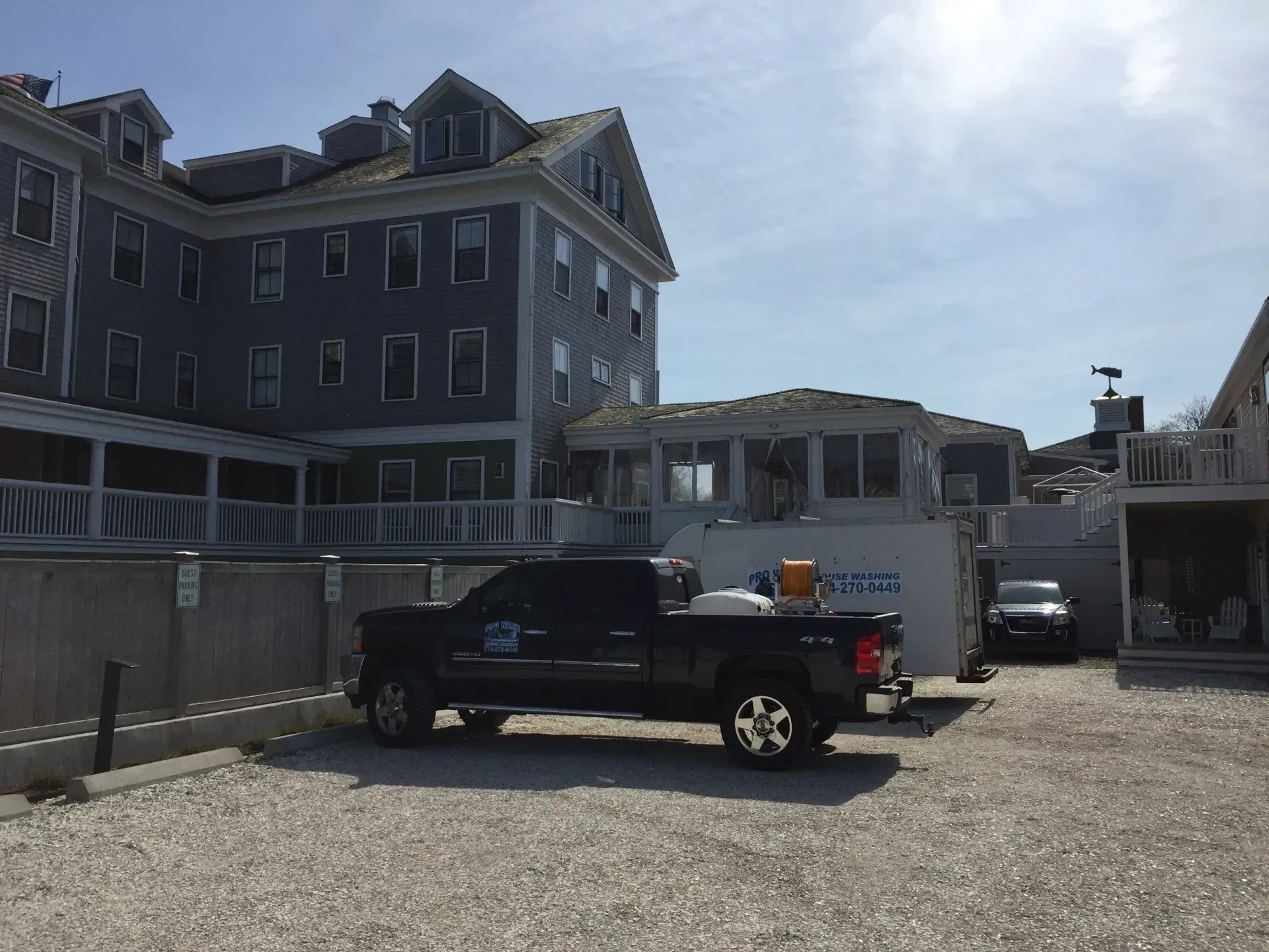 Black pickup truck parked in front of a light gray building on a sunny day.