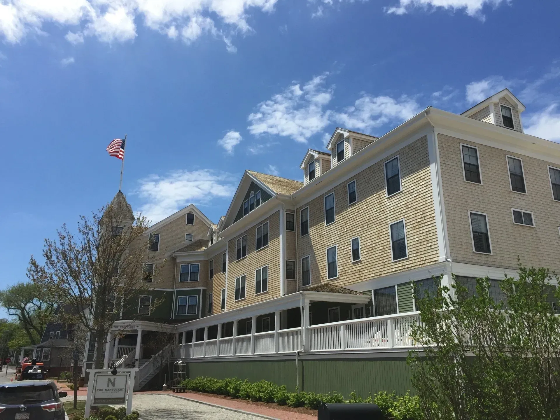 Hotel building with beige siding, white trim, and a U.S. flag against a blue sky.